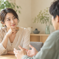 自然光の入る室内で、向き合って話をする2人の実写風イメージ