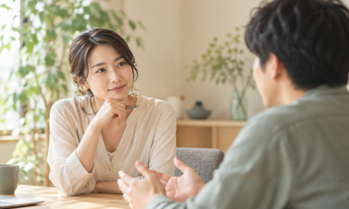 自然光の入る室内で、向き合って話をする2人の実写風イメージ